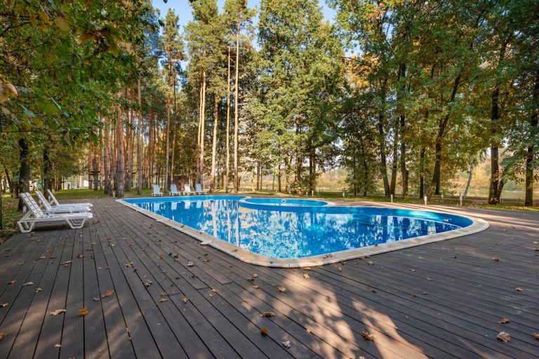 une belle piscine avec une terrasse bois au milieu des pins